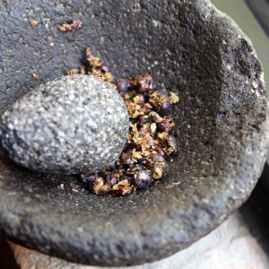 Crushing juniper berries in a molcajete