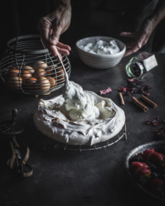 Spooning whipped cream into pavlova