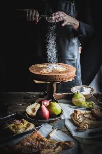 Dusting Powdered Sugar on Pear Cake with Black Pepper and Buttermilk