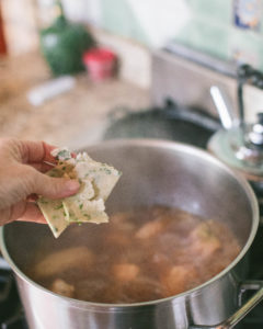 Adding dumplings to simmering pot of Roasted Poblano Chicken and Cilantro Dumplings