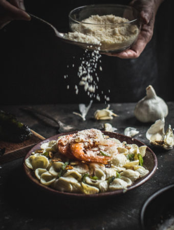 hands sprinkle cheese on Creamy Poblano Pasta with Garlic Shrimp