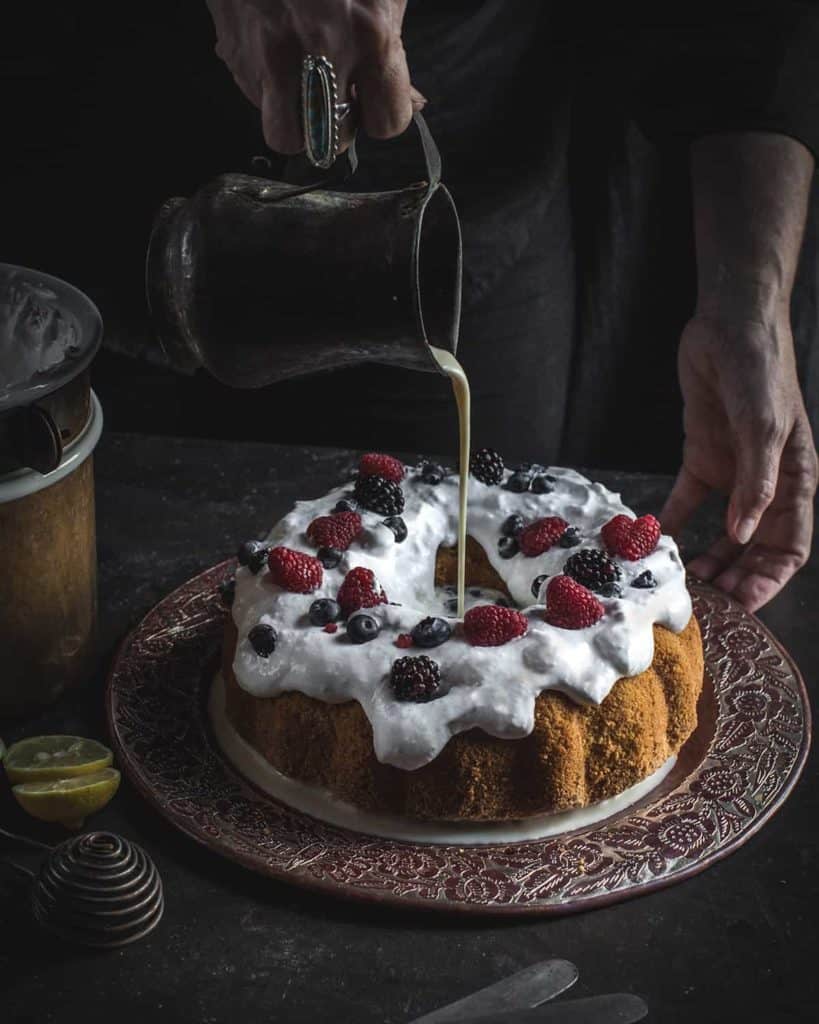 Hand pouring milk on ring cake