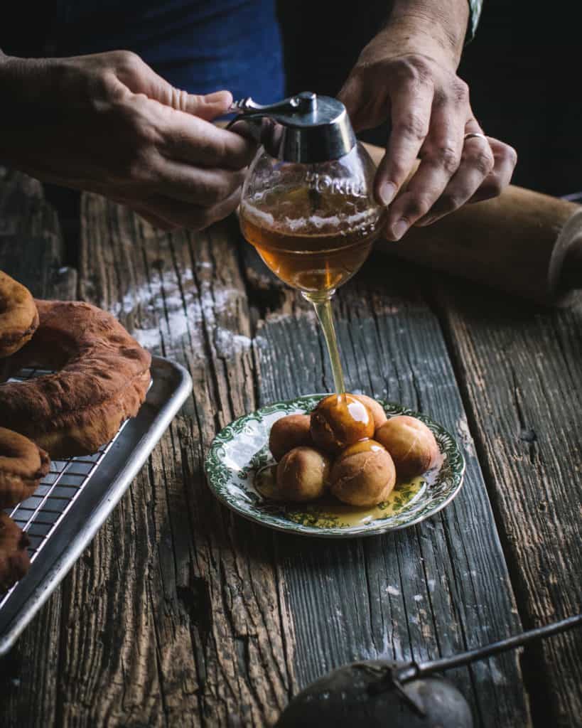 Hands pouring honey on doughnuts