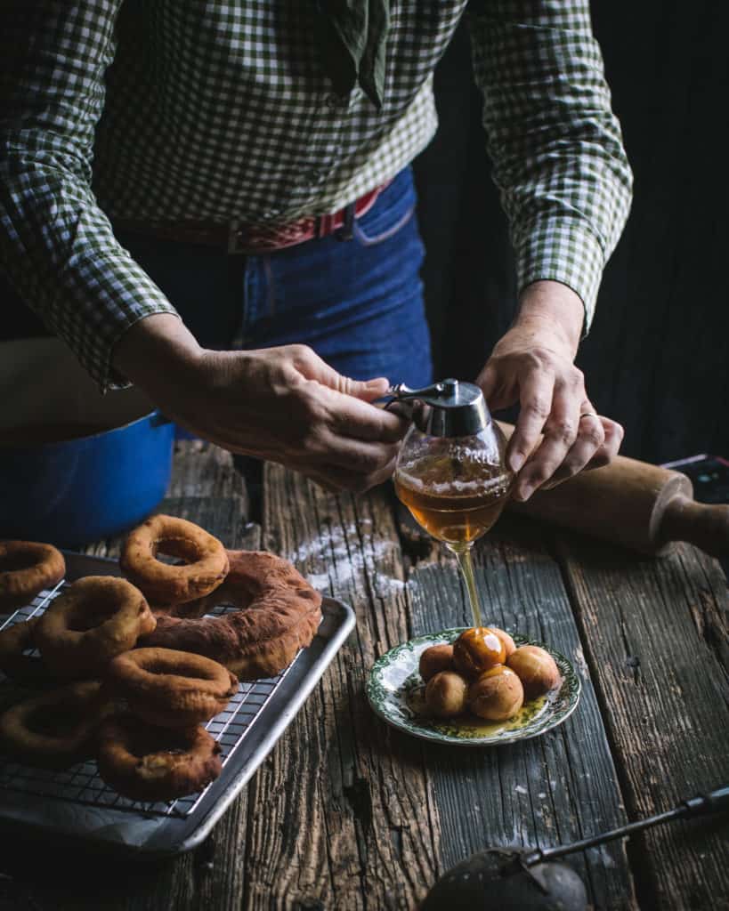 hands pouring honey on doughnuts