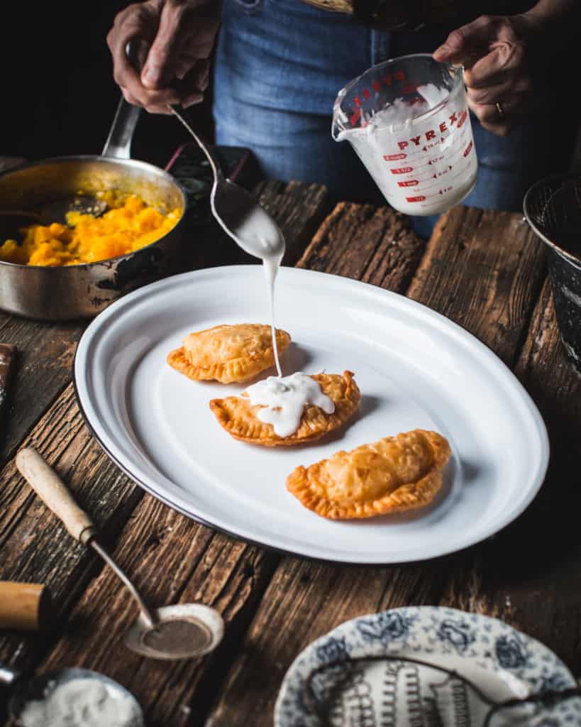 hands pouring glaze over fried pies