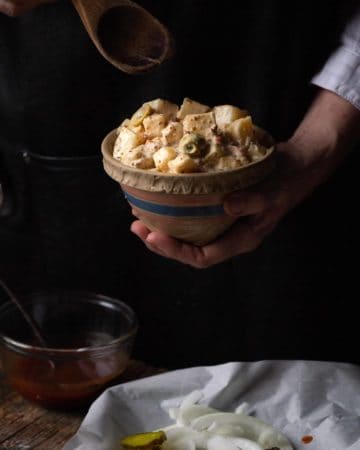 hand with bowl of potato salad