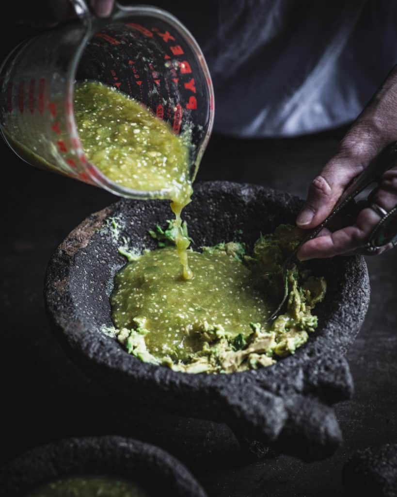 hand adding sauce to bowl