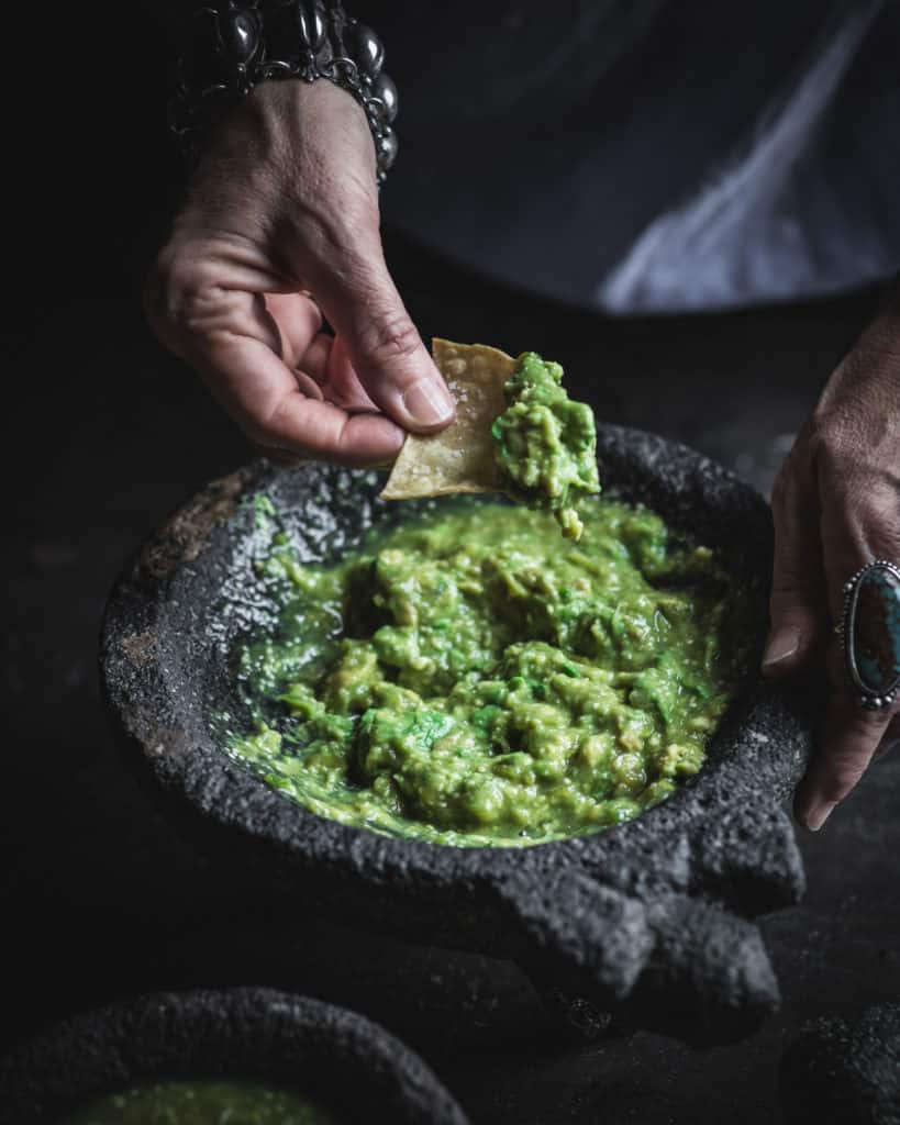 hand with chip in guacamole