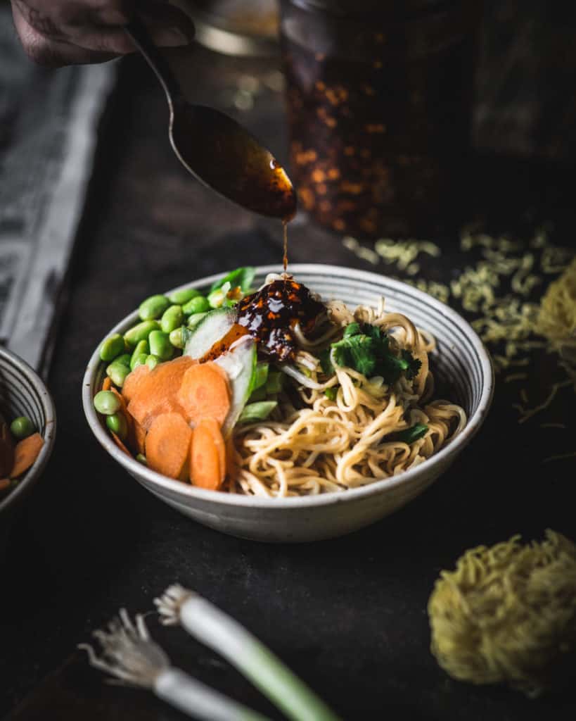 hand adding sauce to bowl