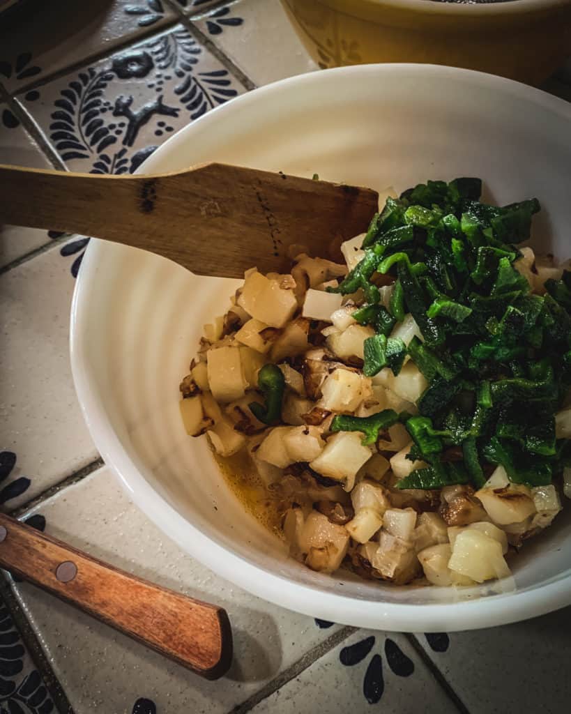 stirring potatoes chiles and eggs in bowl