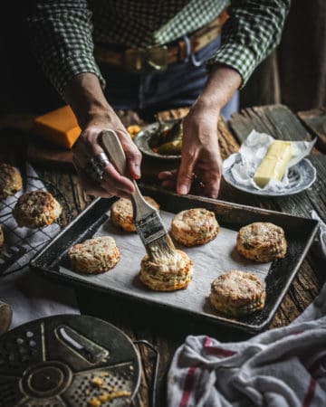 hand brushing butter on biscuit