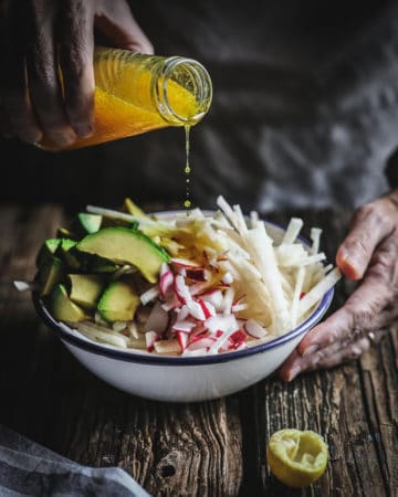 hand pouring dressing on salad