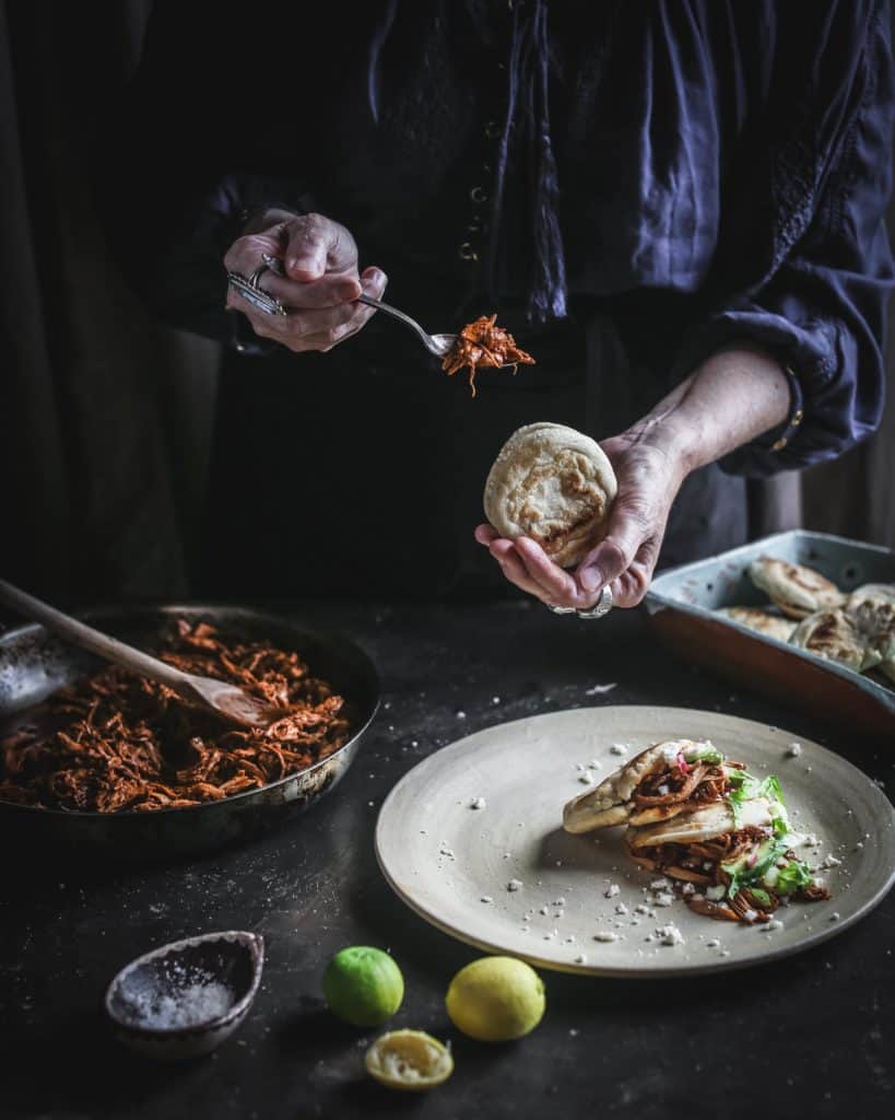 woman filling gorditas with pollo adobado