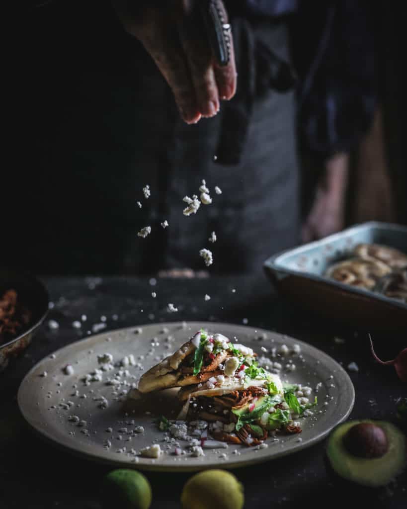 hand sprinkling cheese on gorditas