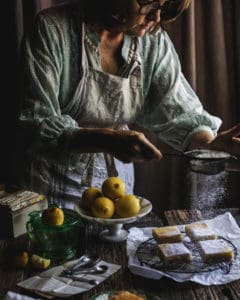 woman garnishing lemon bars
