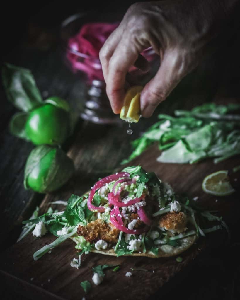 hand squeezing lemon juice on taco