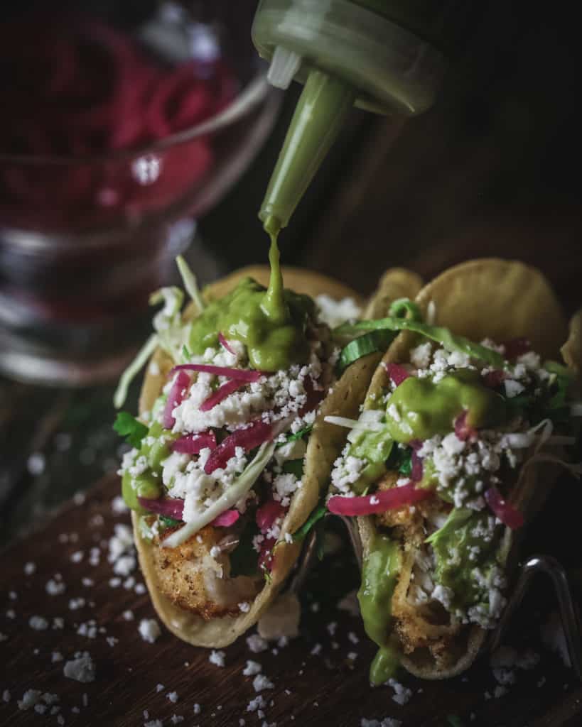 Salsa pouring onto fish taco