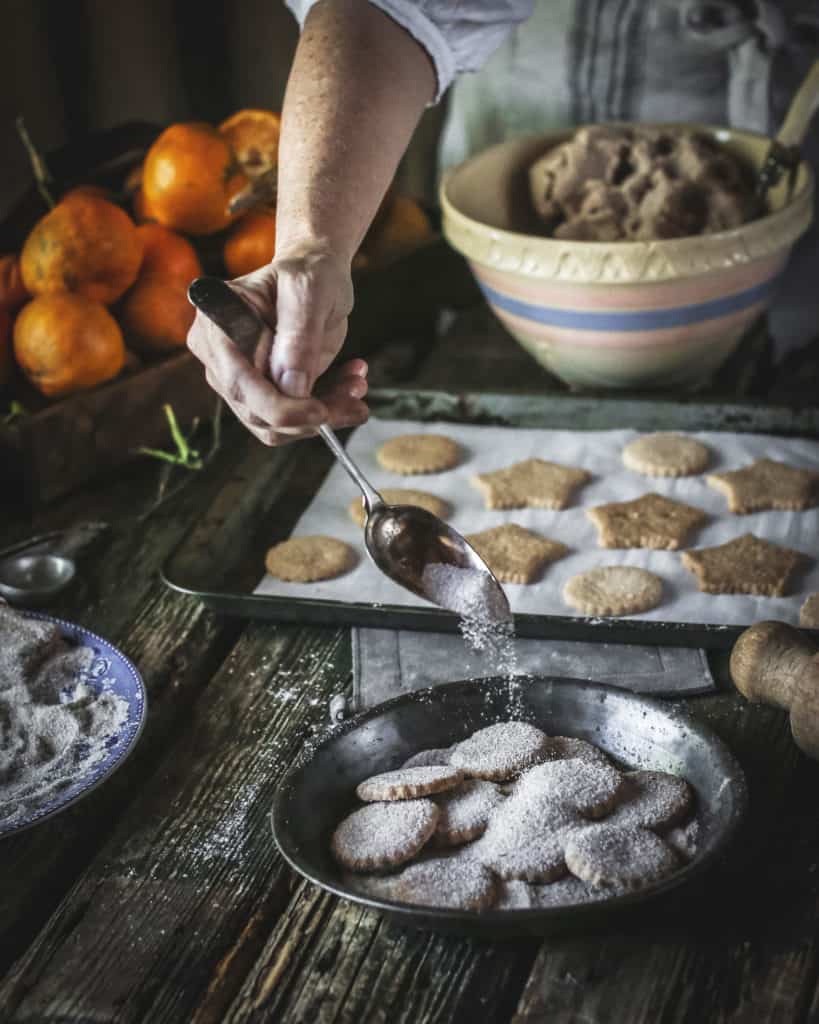 hand sprinkling sugar over cookie