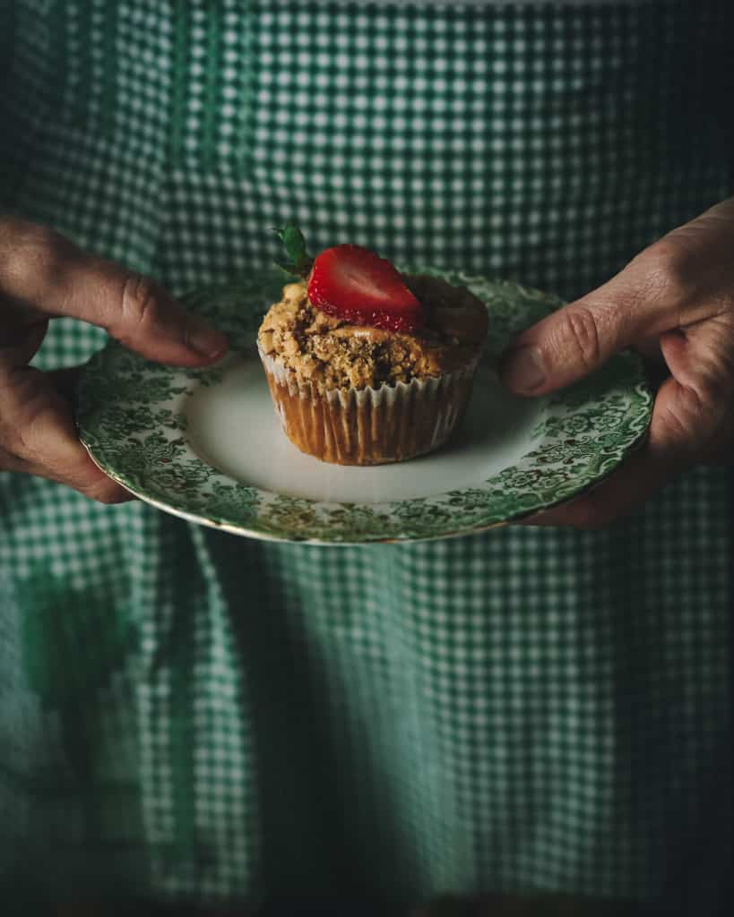 hands holding muffin on a plate