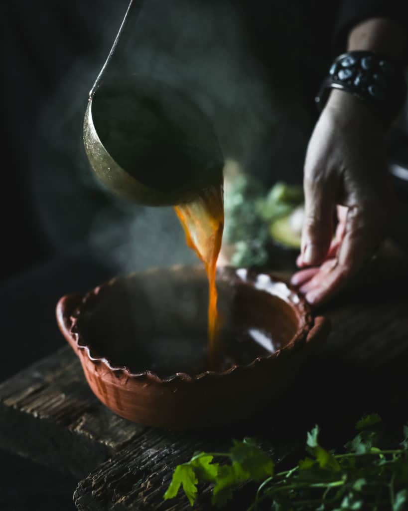 steaming pozole rojo pouring into a bowl