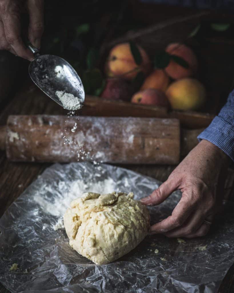hands dusting ball of pie crust with flour