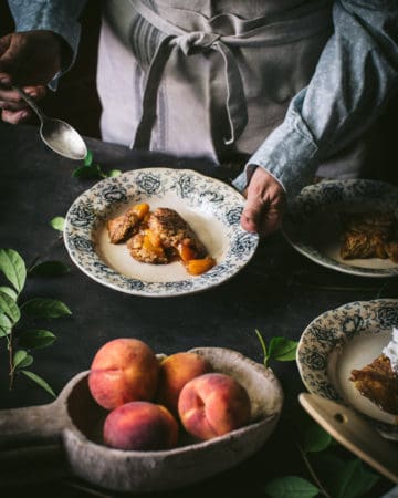 woman serving fresh peach cobbler