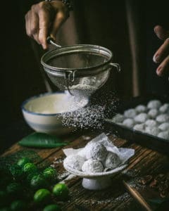 hands sifting sugar over cookies