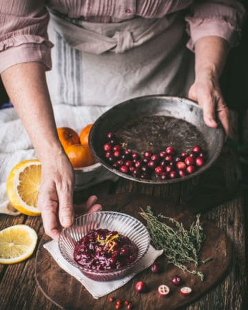 woman serving cranberry sauce with pan of cranberries