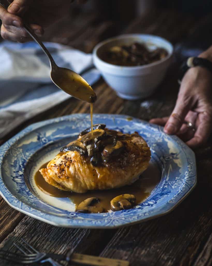 roasted chicken breast on plate spoon pouring sauce
