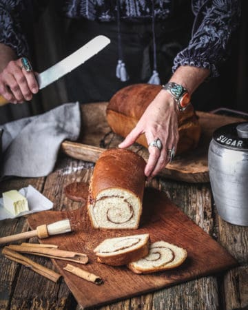 woman slicing loaf of cinnamon swirl bread