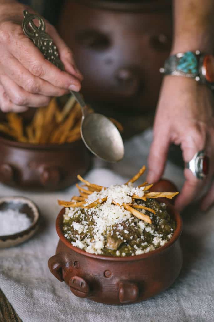 woman spooning out chili verde out of bowl