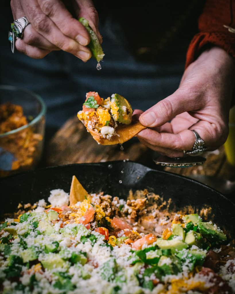 woman squeezing lime juice on tortilla chip