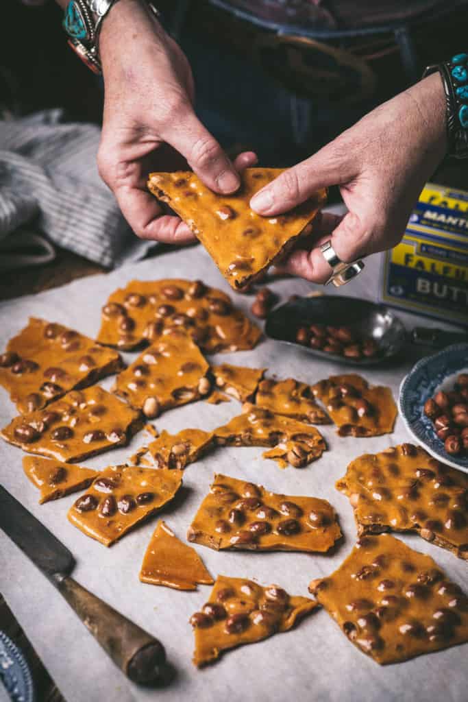 woman holding piece of peanut brittle