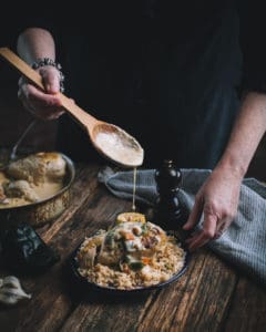 woman spooning sauce on chicken in poblano cream sauce