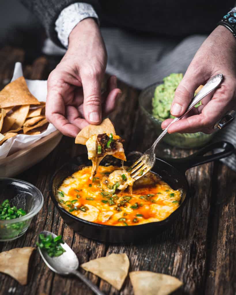 woman dipping tortilla chip in choriqueso