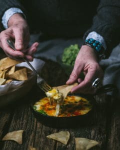 woman dipping tortilla chip in choriqueso