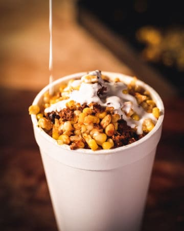 cream pouring on chorizo corn in a cup