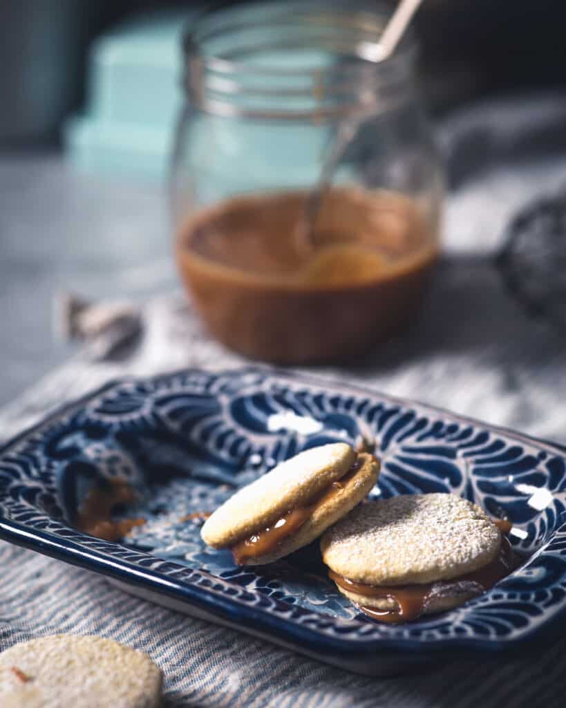 dulce de leche filling dripping from stacked alfajores cookie