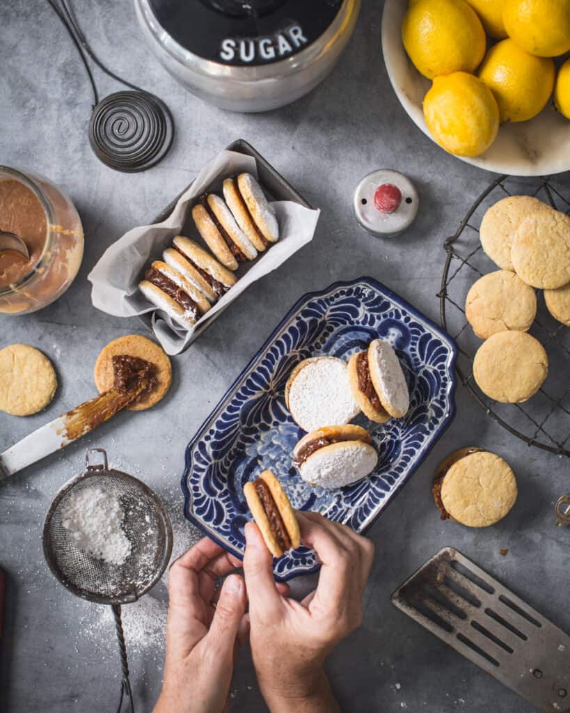 overhead pic of hands serving alfajores cookies