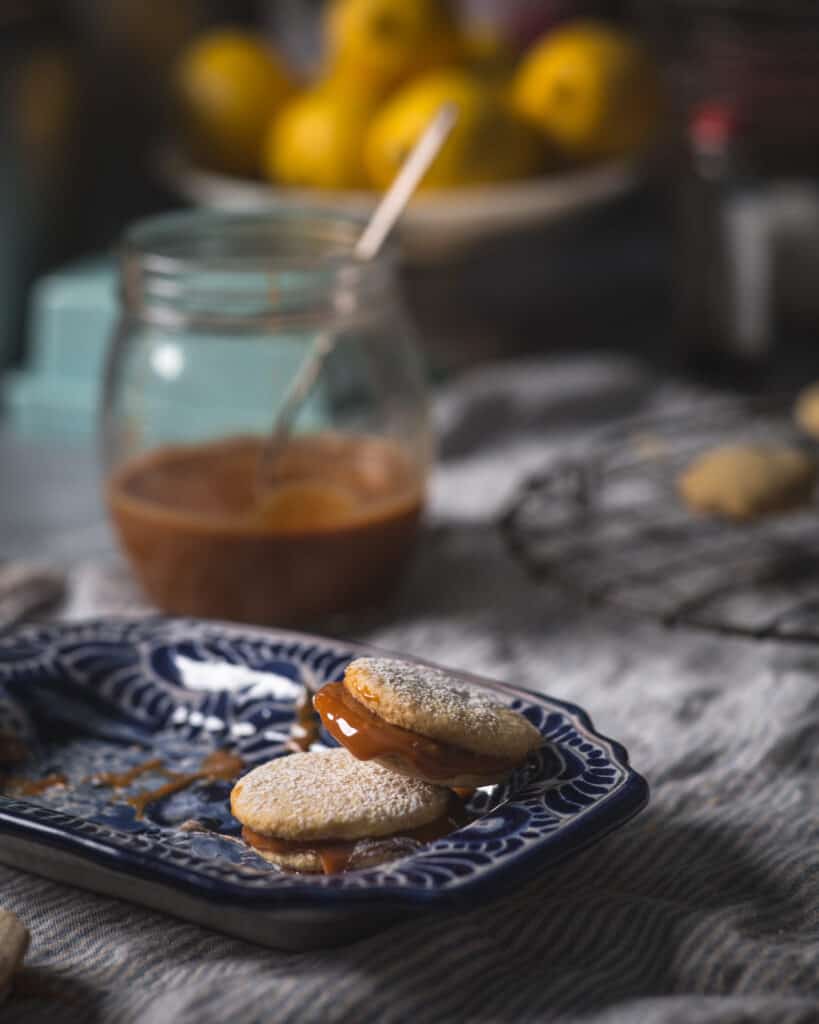 dulce de leche filling dripping from stacked alfajores cookie