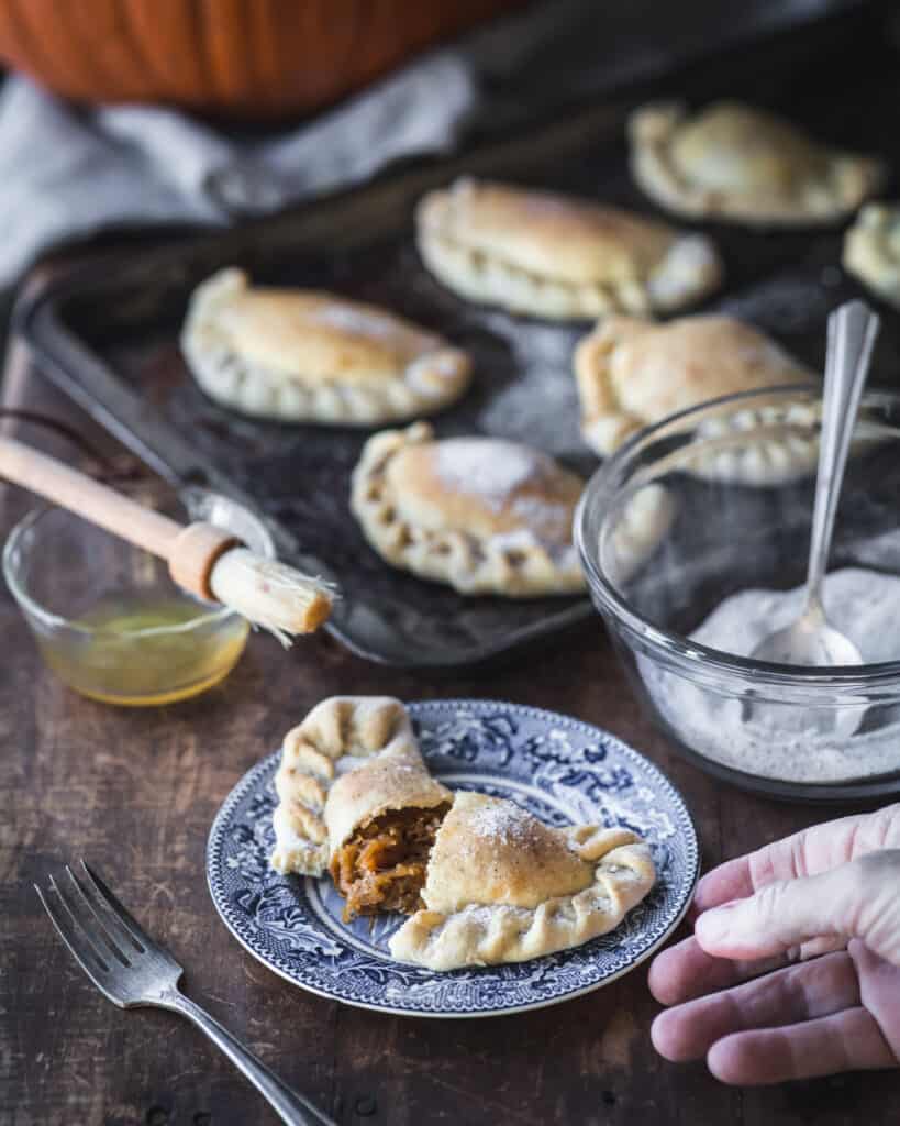 hand reaching for pumpkin empanada