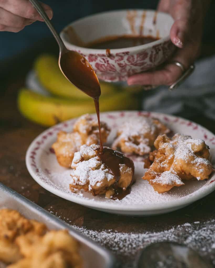 hand drizzling dulce de leche over fritters