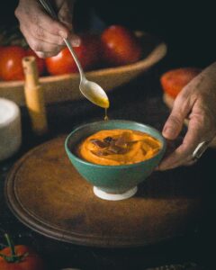 olive oil dripping into bowl of chilled tomato soup