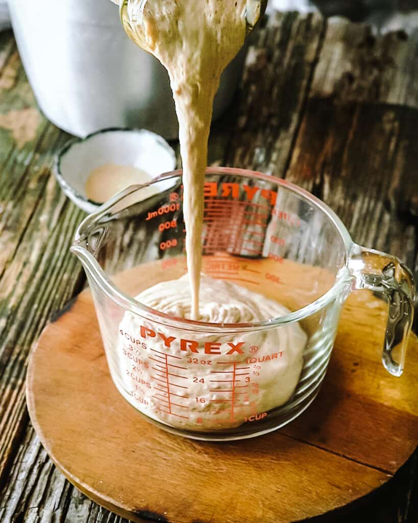 sourdough starter pouring into measuring cup