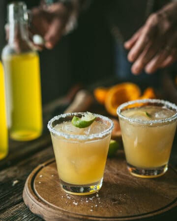 woman behind two paloma cocktail glasses