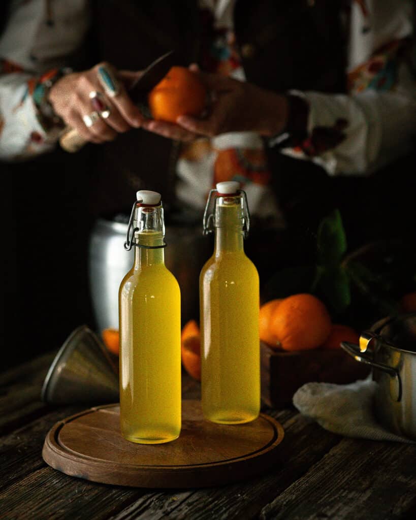 woman carving orange behind bottles of syrup