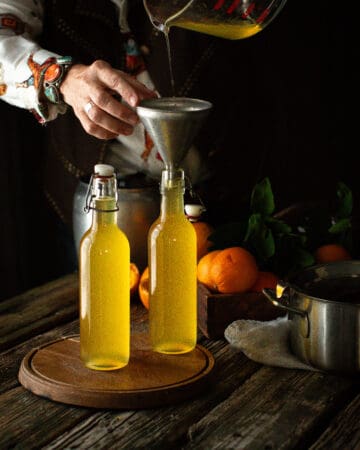 woman using funnel to fill bottles of Orange Simple Syrup