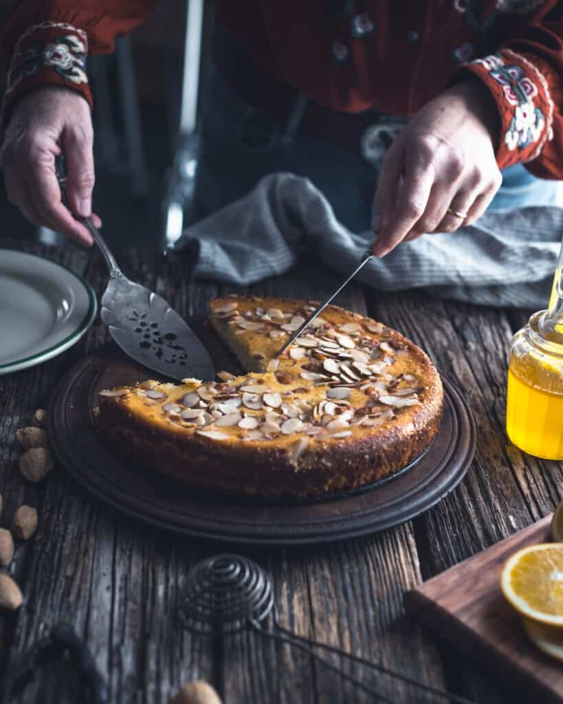 woman cutting wedge of Orange Almond Cake