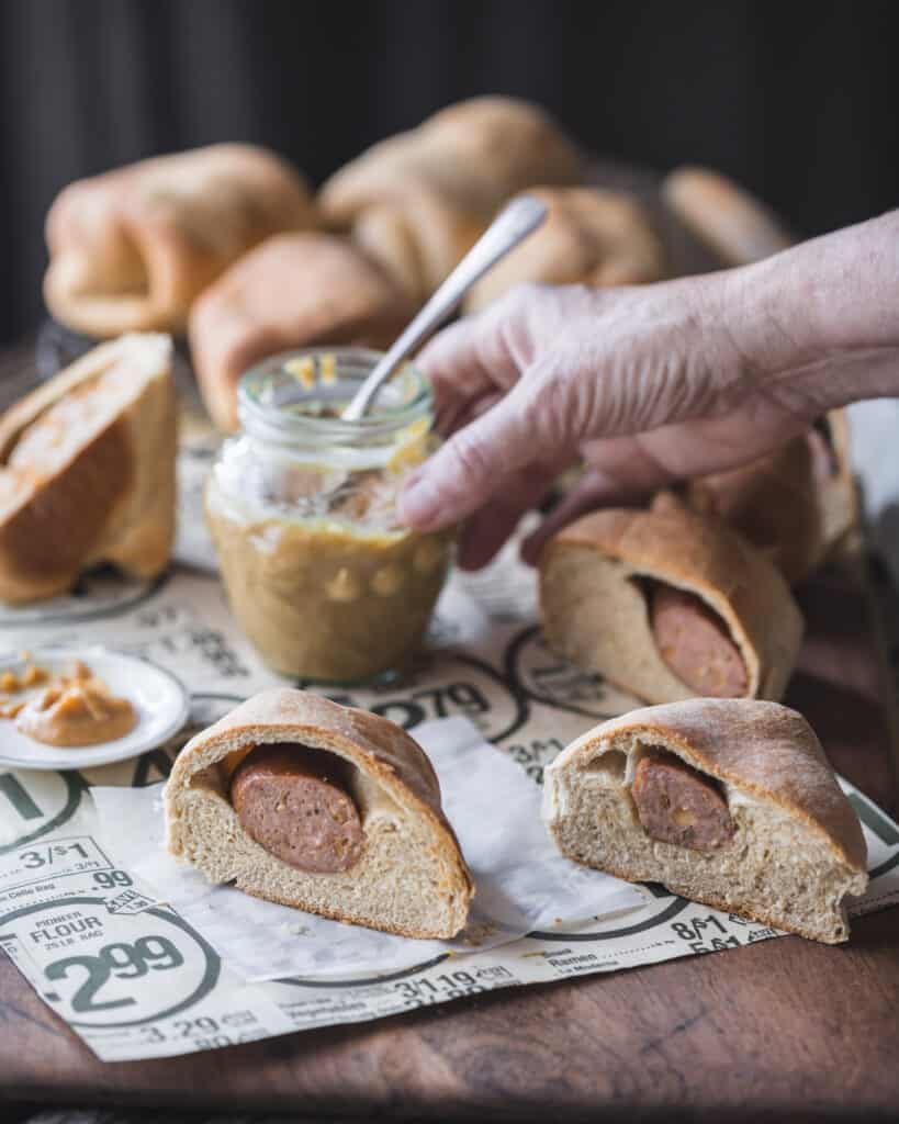 hand reaching for jar of mustard behind kolache