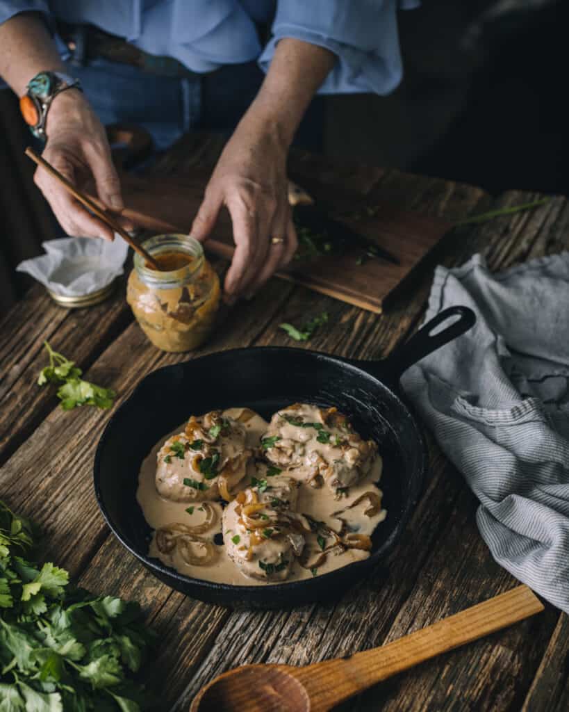 Womans hands behand pan of mustard chicken